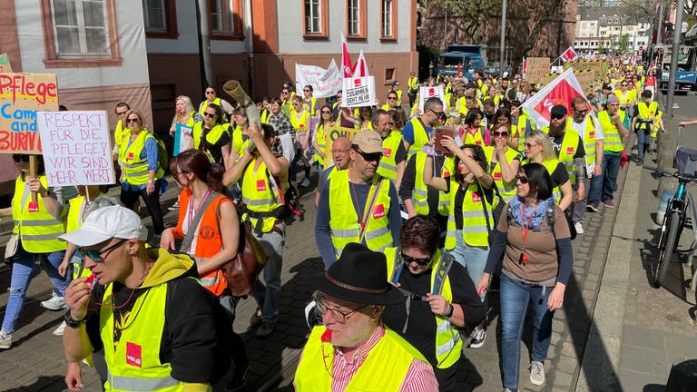 Mit Fahnen, Transparenten und Trillerpfeifen ziehen Beschäftigte der Unimedizin in gelben Warnwesten durch die Mainzer Innestadt, um für mehr Geld zu protestieren (Foto: SWR)