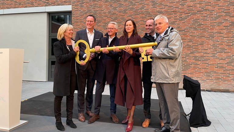 Die Ehrengäste halten einen großen goldenen Schlüssel für das Leibniz-Zentrum in der Hand (Foto: SWR, Leonie Berger)