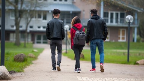 Drei Jugendliche sind von hinten zu sehen, während sie auf ein Haus zulaufen. (Foto: picture-alliance / Reportdienste,  Philipp Schulze)