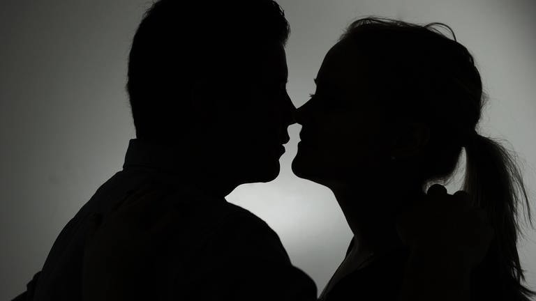 Ein Mann und eine Frau küssen sich. Immer wieder fallen Menschen auf der Suche nach der großen Liebe aber auf Betrüger herein.  (Foto: dpa Bildfunk, picture alliance / dpa | Jan-Philipp Strobel)