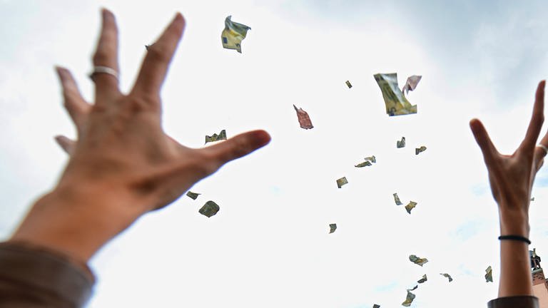 Ausgestreckte Hände versuchen flatternde Geldscheine aus der Luft zu fangen. (Foto: dpa Bildfunk, picture alliance / dpa | Andreas Arnold)