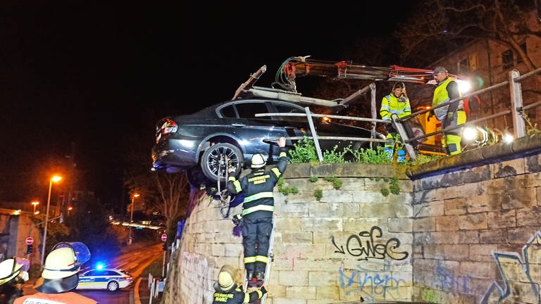 Das Auto ist oberhalb einer Bahnunterführung durch ein Treppengeländer gebrochen und hängt mit den Hinterrädern in der Luft. (Foto: BYC-News)