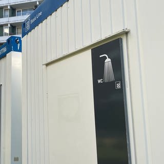 Das Hochhaus in Mainz-Weisenau, davor die Container: Die Wasserleitungen müssen saniert werden. Die rund 50 Bewohnerinnen und Bewohner müssen draußen duschen und auf Toilette (Foto: SWR)