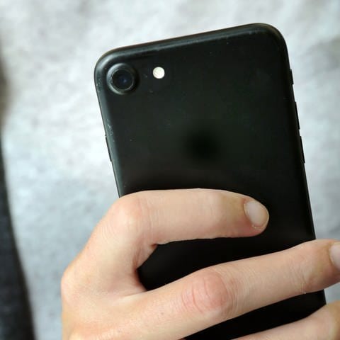 Eine Frau filmt mit ihrem schwarzen Smartphone. Der Fokus liegt auf dem Handy und die Hand. Das Display kann man nicht sehen. (Foto: dpa Bildfunk, Fernando Gutierrez-Juarez)