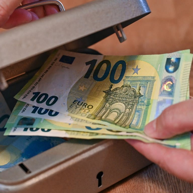 Eine Frau holt mehrere 100 Eurobanknoten aus einer kleinen Geldkassette. Die Aufnahme wurde für das Foto gestellt.  (Foto: dpa Bildfunk,  Patrick Pleul (Symbolbild))