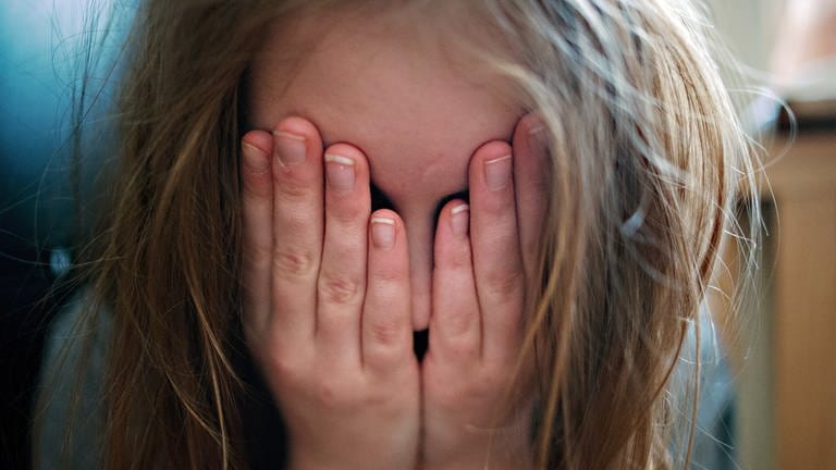 Ein junges Mädchen hält sich die Hände vor ihr Gesicht.  (Foto: dpa Bildfunk, Nicolas Armer)