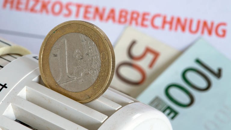 Eine Ein-Euro-Münze vor einem Stapel mit Heizkostenabrechnungen