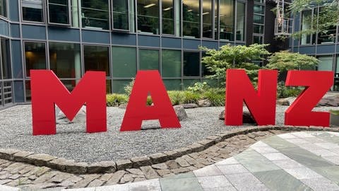 Vier rote  Buchstaben stehen im Innehof des Mainzer Stadthauses. Es sind ein M,ein A, ein N und ein Z. Es fehlt ein I. (Foto: SWR, C. Lutz)