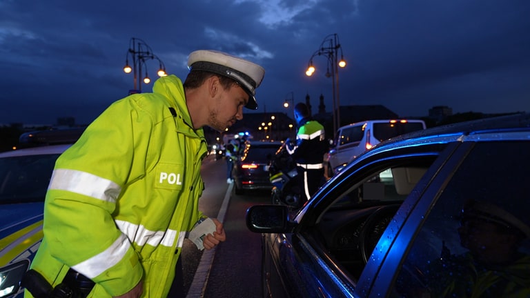 Ein Mainzer Polizist steht am geöffneten Fenster eines Autos und spricht mit dem Fahrer. (Foto: SWR)