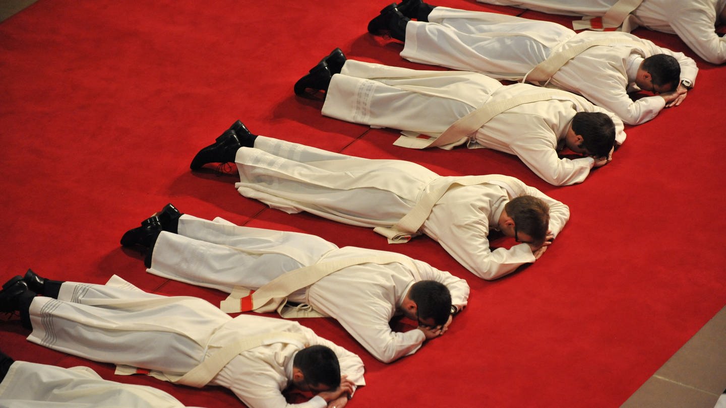 Priesteranwärter des Erzbistums Freiburg liegen am Sonntag (09.05.2010) während ihrer Weihe zum Priester als Zeichen der Demut bäuchlings auf einem roten Teppich im Freiburger Münster. (Foto: dpa Bildfunk, picture alliance / dpa | Rolf Haid)