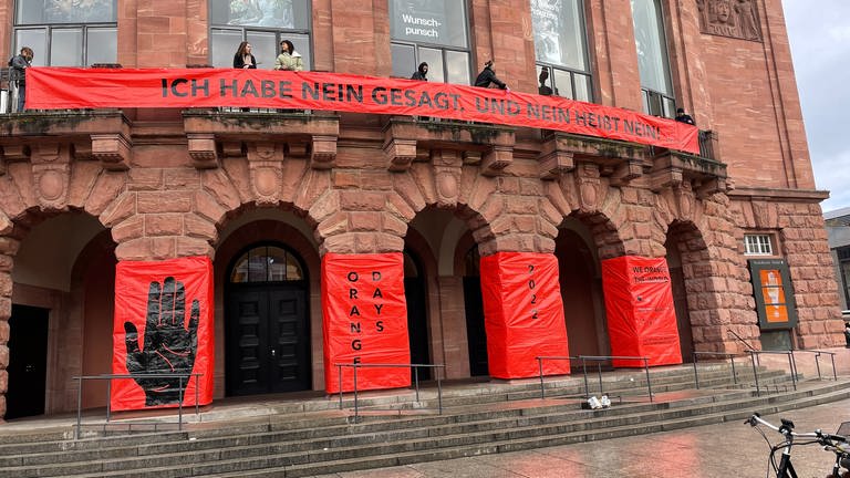 Am Staatstheater in Mainz sind orange Banner angebracht, auf denen ein Ende der Gewalt gegen Frauen gefordert wird