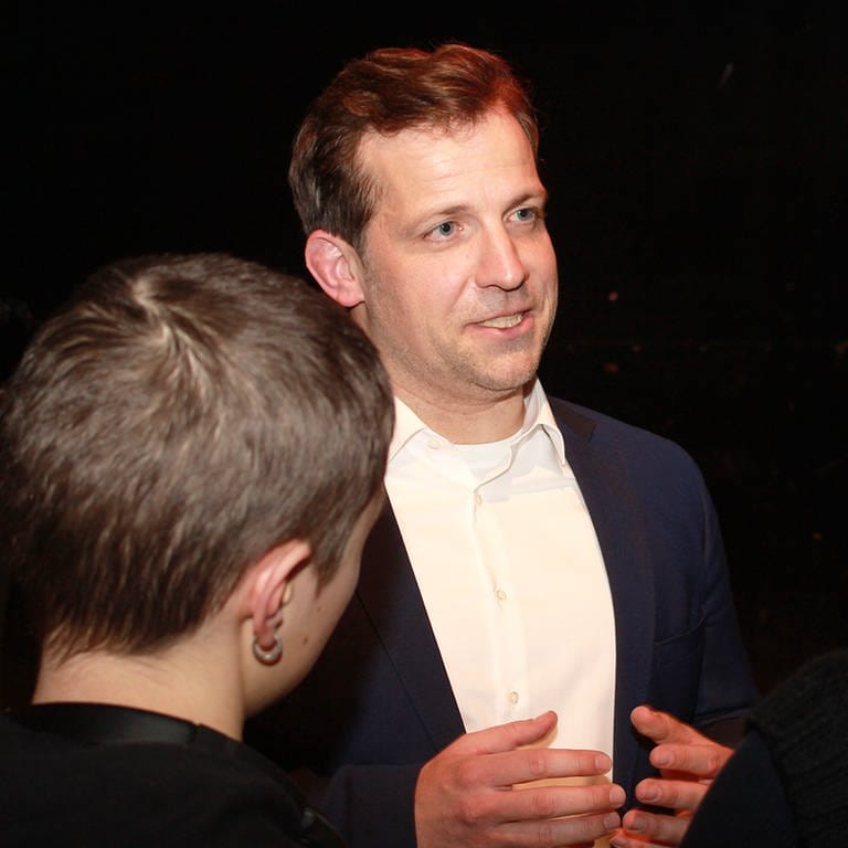 Der parteilose Kandidat bei der Mainzer OB-Wahl, Nino Haase, im Gespräch mit drei Menschen auf einer Wahlkampfveranstaltung.