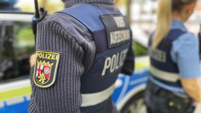 Zwei Polizisten in Uniform stehen in Mainz vor einem Polizeiauto. (Foto: SWR, D. Brusch)