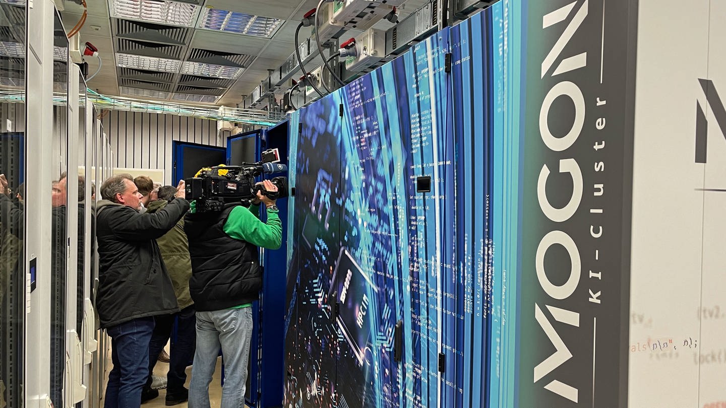 In Mainz wurde der neue Hochleistungsrechner Mogon eingeweiht. Der Rechner sieht unspektakulär aus - wie eine große Schrankwand. Journalisten versuchen mit ihren Kameras dennoch ein ansprechendes Bild zu machen. (Foto: SWR, G. Schlenk)