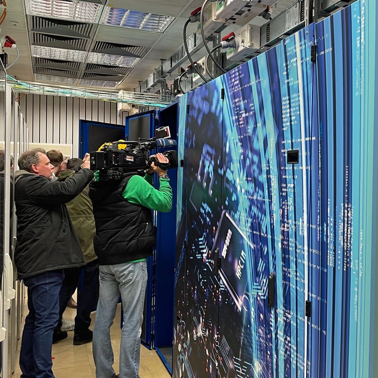 In Mainz wurde der neue Hochleistungsrechner Mogon eingeweiht. Der Rechner sieht unspektakulär aus - wie eine große Schrankwand. Journalisten versuchen mit ihren Kameras dennoch ein ansprechendes Bild zu machen.  (Foto: SWR, G. Schlenk)