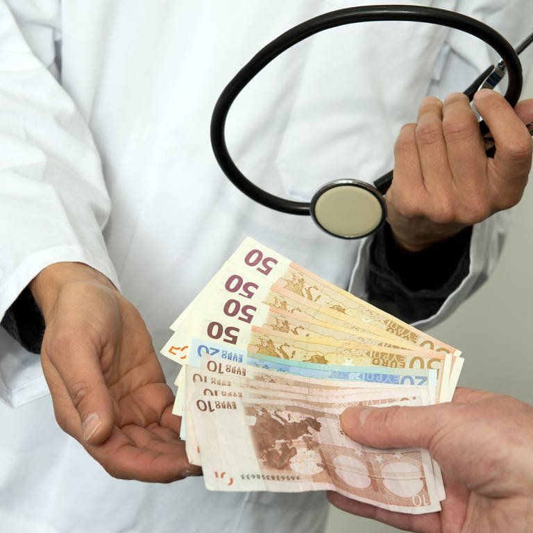 Ein Arzt hält die Hand auf und bekommt mehrere Euro Scheine gereicht. (Foto: picture-alliance / Reportdienste, Picture Alliance)