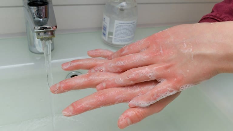 Ein Mädchen wäscht sich die Hände mit Wasser und Seife.