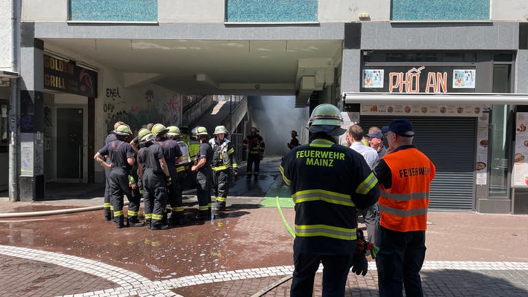 Mainzer Feuerwehrleute stehen vor dem Eingang einer Tiefgarage.