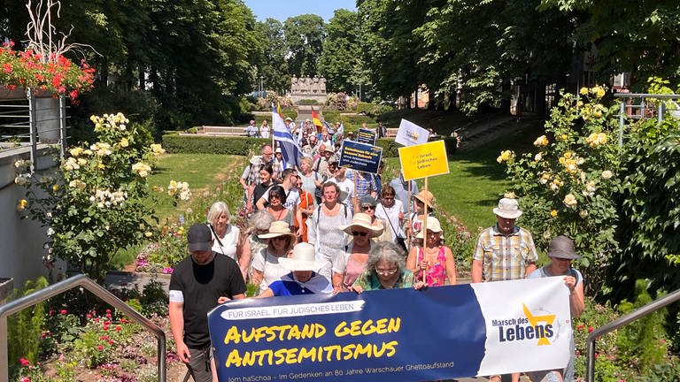 Menschen tragen beim Marsch des Lebens Plakat mit Aufschrift "Aufstand gegen Antisemitismus"