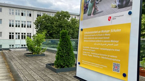 Auf einem Plakat informiert die Stadt Mainz in mehreren Sprachen über die Sozialarbeit an staatlichen Schulen. Es wird unter anderem erklärt, dass sowohl in Einzelfällen geholfen als auch mit Klassen und Gruppen gearbeitet wird. 