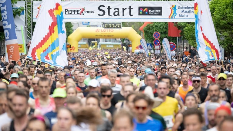 Eine riesige Menschenmenge läuft beim Gutenberg-Marathon los, in Hintergrund ein großes Banner, auf dem Start steht.