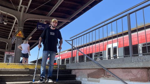 Ein junger Mann mit Krücken muss über die Treppe zum Bahnsteig in Bad Münster am Stein-Ebernburg 