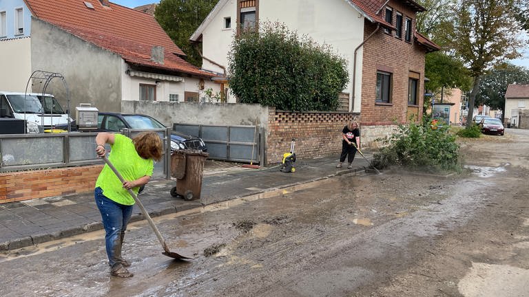 In Worms-Pfeddersheim kratzen und spülen Frauen den Schlamm von den Straßen. Regen und Hagel hatten in und um Worms am Dienstagabend schwere Schäden angerichtet. (Foto: SWR, Sarina Fischer)