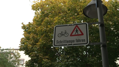 Straßenschild warnt Radfahrer, langsam zu fahren, weil Fußgänger den Weg kreuzen