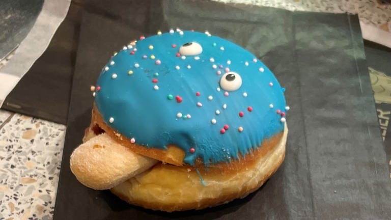 Kreppel mit blauem Zuckerguss liegt auf einer Bäckertüte (Foto: SWR)