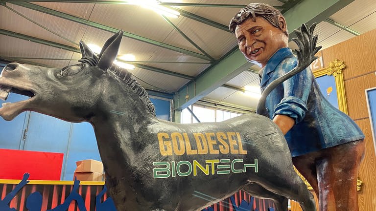 Der Mainzer Finanzdezernent Beck greift einem Goldesel mit der Aufschrift "Goldesel" Biontech in den Hintern