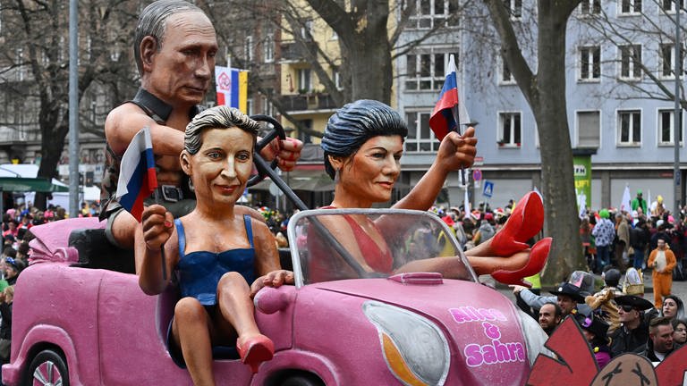 Der MCV-Motivwagen "Barbies und Ken", der Alice Weidel (AfD, 2.v.l), den russischen Präsidenten Wladimir Putin und Sahra Wagenknecht (BSW) aufs Korn nimmt, ist beim Mainzer Rosenmontagszug unterwegs. (Foto: dpa Bildfunk, Arne Dedert)