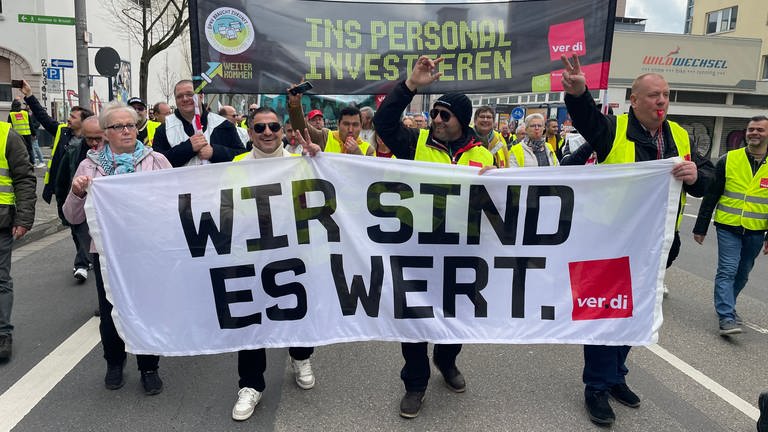 Demonstrierende tragen ein Transparent mit der Aufschrift "Wir sind es wert"