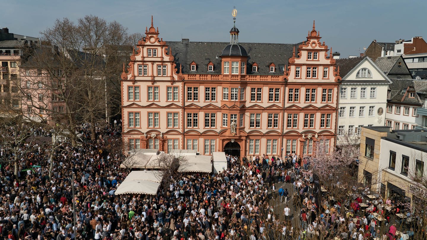 Luftaufnahme vom Marktfrühstück in Mainz. Der Weinausschank befindet sich vor dem Gutenberg-Museum.Hunderte Menschen stehen davor und trinken ein Glas Wein oder Saft.mainz (Foto: SWR)