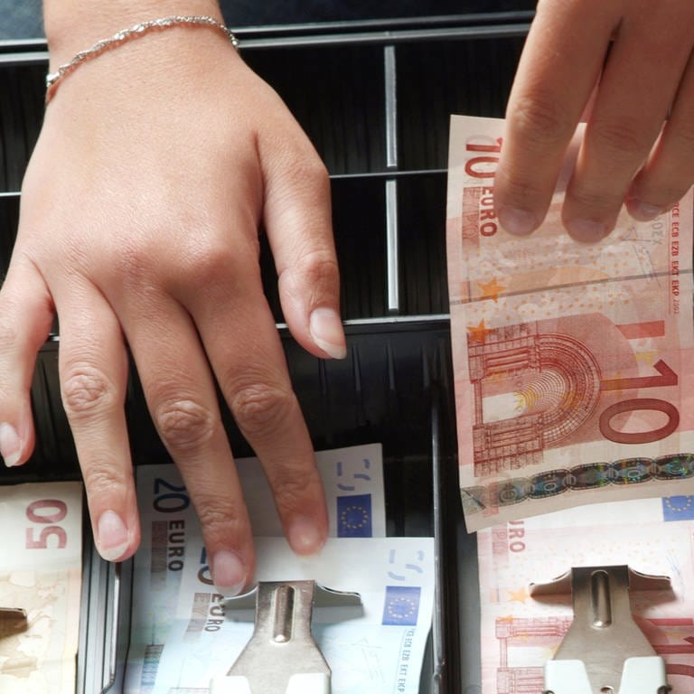 Eine Hand zieht Geldscheine aus einer Kasse. (Foto: picture-alliance / Reportdienste, picture alliance / Caro | Conradi (Symbolbild))