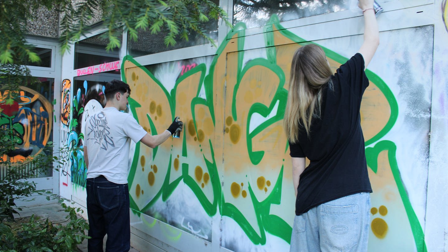 Zwei Jugendliche besprühen das alte Hallenbad in Oppenheim mit buntem Graffiti. (Foto: SWR, Ben Bukes)