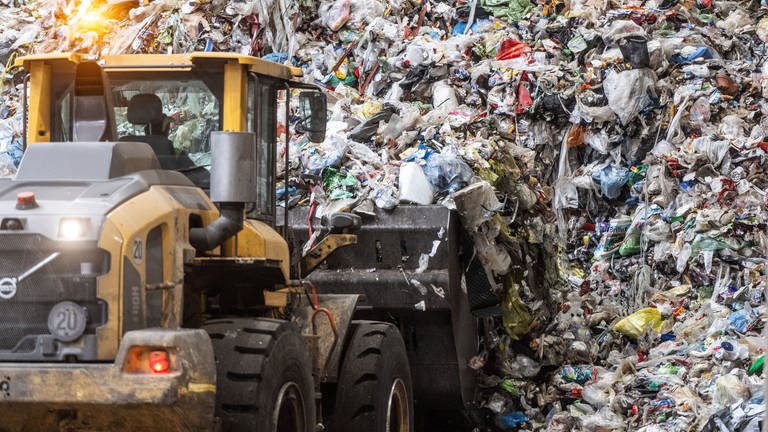 Ein Radlader transportiert Müll aus Gelben Säcken in eine Sortieranlage, das Plastik wird zum Teil recycelt.