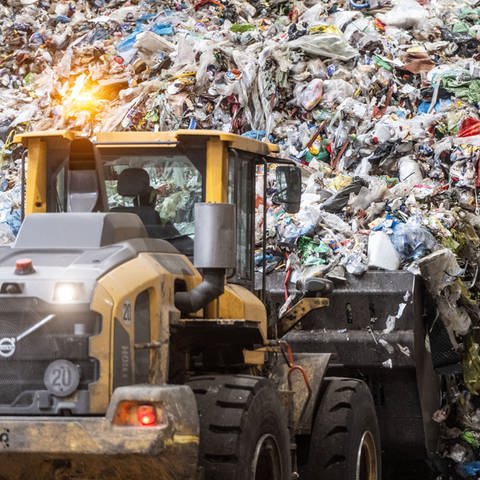Ein Radlader transportiert Müll aus Gelben Säcken in eine Sortieranlage, das Plastik wird zum Teil recycelt.