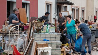 Menschen räumen im Stadtteil Ehrang die Schäden nach dem Hochwasser der Kyll auf. Zahlreiche Häuser im Ort waren betroffen, Bewohner mussten evakuiert werden. (Foto: dpa Bildfunk, picture alliance/dpa | Harald Tittel)