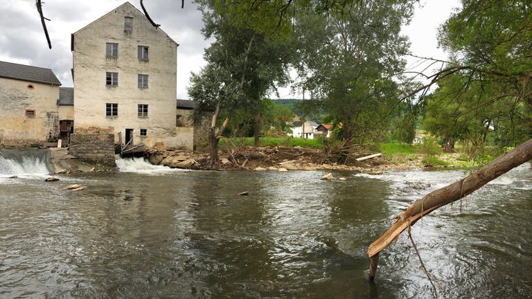 An der Mühle in Peffingen wurden bereits viele Äste weggeräumt. Vor allem wurden die Straßenränder der Brücke daneben und die Ufer wieder befestigt und aufgeschüttet mit Schotter (Foto: SWR, Lara Bousch)