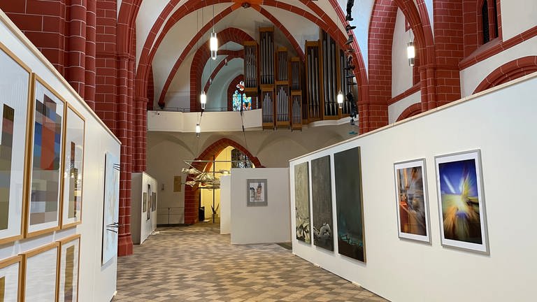 Zu sehen sind Darstellungen der Gangolfkirche, teils gemalt, teils fotografiert. Aber die Kirche hat viele der teilnehmenden Künstlerinnen und Künstler auch zu abstrakten Werken inspiriert. (Foto: SWR, Nicole Mertes)