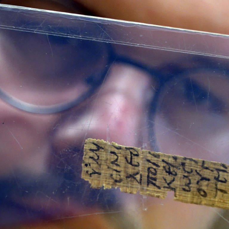 Patrick Reinard betrachtet ein Papyrus-Fragment. (Foto: SWR, Universität Trier)