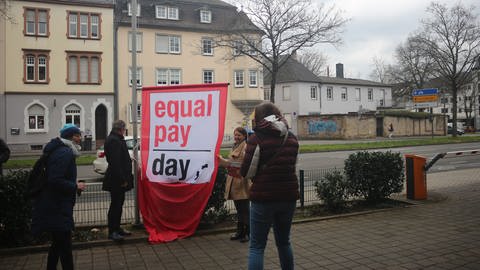Der Landrat des Kreises Trier-Saarburg, Stefan Metzdorf (SPD, links), und die Gleichstellungsbeauftragte des Kreises, Angelika Mohr (rechts), hissen die Flagge zum Equal Pay Day. (Foto: SWR, Saskia Schleyer)