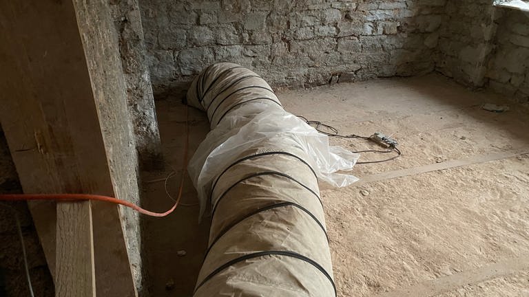Mit einem Schlauch wird die Wärme aus der Zeltheizung in die Räume des Hauses geleitet. Damit werden die Wände getrocknet.