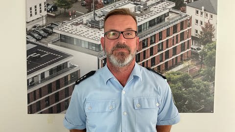 Stefan Döhn ist Pressesprecher der Bundespolizei Trier, deren Inspektionsgebäude auf dem Bild im Hintergrund zu sehen ist.  (Foto: SWR)