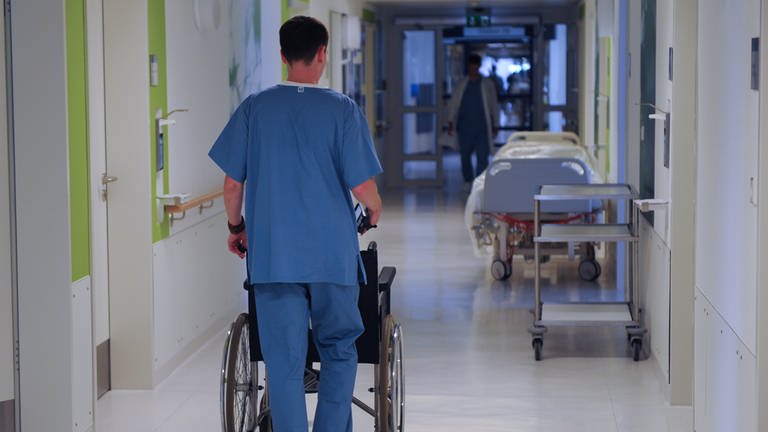 Pfleger schiebt Patienten über Krankenhausflur (Foto: picture-alliance / Reportdienste, Peter Steffen)