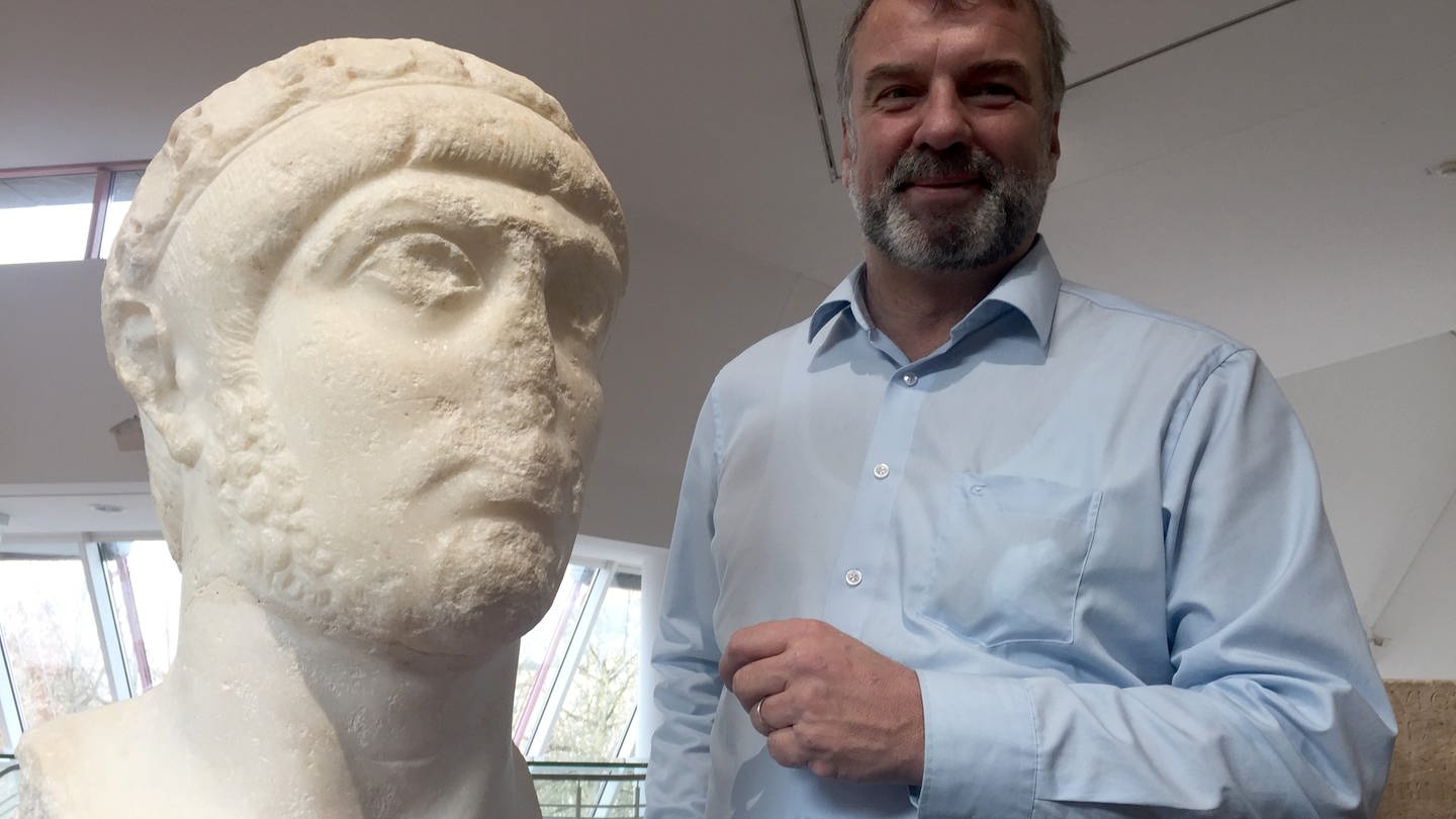 Der Direktor des Rheinischen Landesmuseums Trier, Marcus Reuter, steht im Rheinischen Landesmuseum neben einem Marmor-Porträt des Kaisers Gratian. (Foto: picture-alliance / Reportdienste, dpa | Birgit Reichert)
