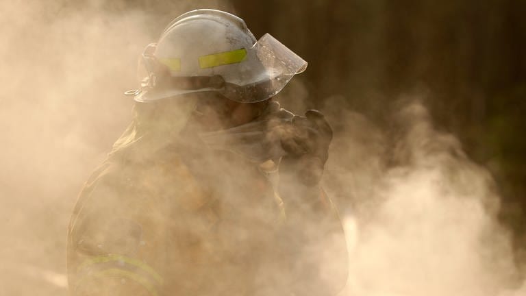 Ein Feuerwehrmann steht bei einem Brand in dichtem Rauch. (Foto: dpa Bildfunk, Rick Rycroft)