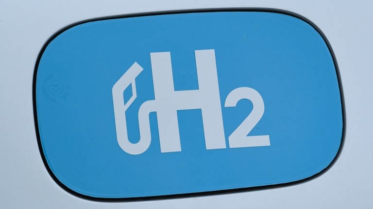 Das chemische Elemet "H2" für Wasserstoff ist auf einem Tankdeckel eines mit Wasserstoff angetriebenen Autos zu sehen.