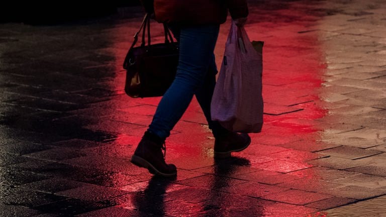 Frau läuft im Dunkeln mit Einkaufstaschen durch eine Fußgängerzone (Foto: picture-alliance / Reportdienste, Daniel Bockwoldt)