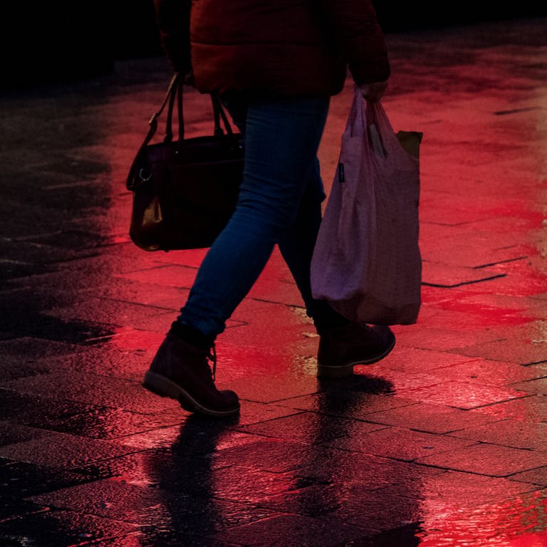 Frau läuft im Dunkeln mit Einkaufstaschen durch eine Fußgängerzone (Foto: picture-alliance / Reportdienste, Daniel Bockwoldt)